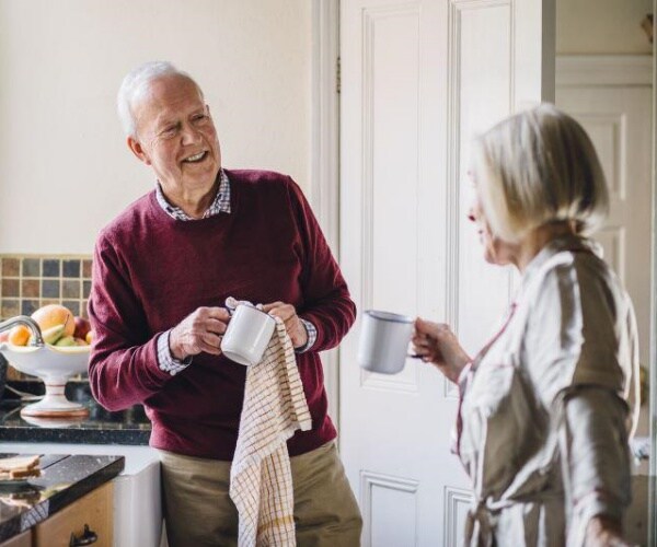 older man and woman in kitchen talking and having coffee in morning