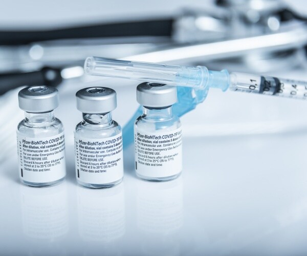 three vials of Pfizer COVID vaccine and a syringe