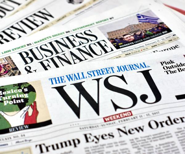 sections of the wall street journal spread out on a table with a headline about trump on the front page