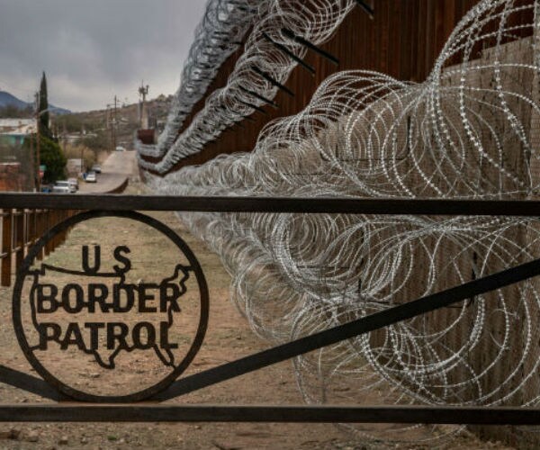 razor wire at the border and a gate with u s border patrol written on it