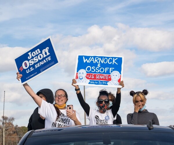 young activists hold up signs in support of ossoff and warnock