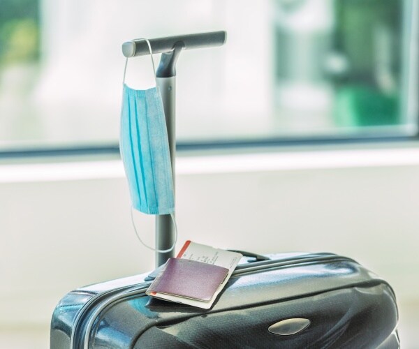 luggage with passport and mask on top of it in an airport