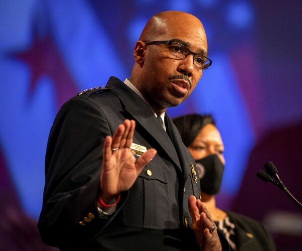 contee in a black police uniform speaking in front of a mic