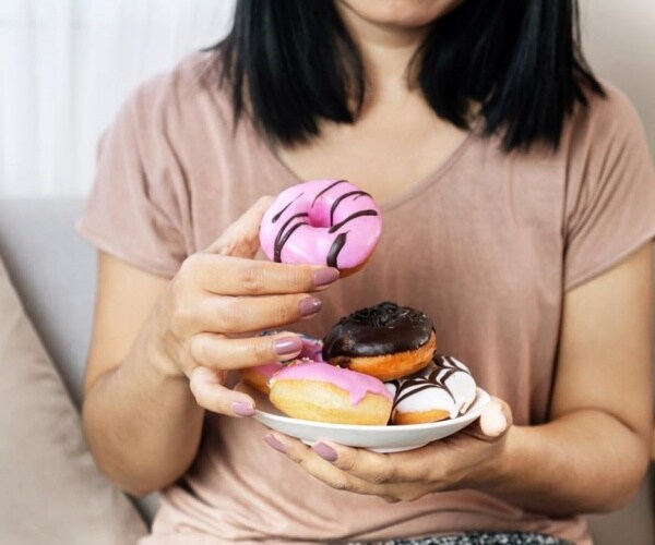 woman holding a plate with several donuts