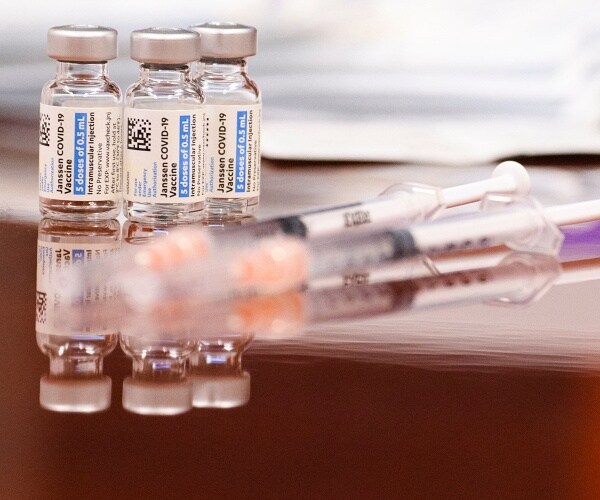 three vials of vaccine and 3 needles sit on table