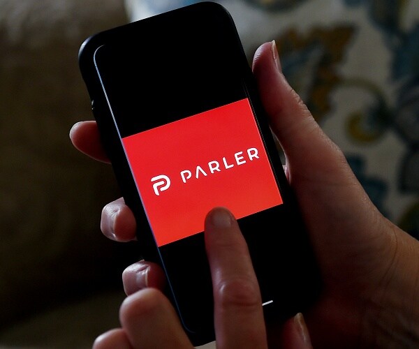 man holding phone with parler app on screen