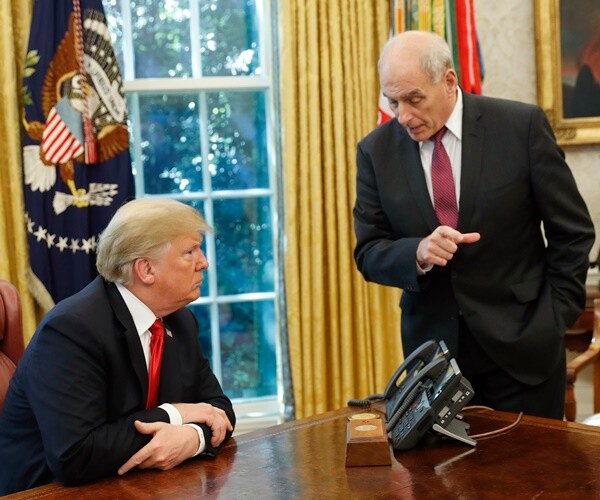 john kelly stands next to president trump desk and speaks with him.