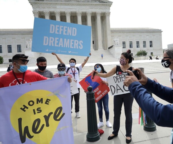 people wearing masks hold up signs in support of dreamers