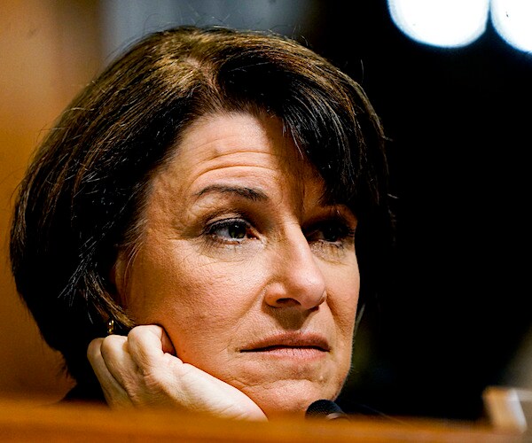 minnesota democratic senator amy klobuchar rests her chin in her right palm while listening to senate testimony