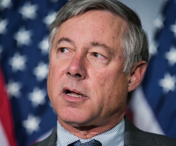 fred upton in a dark gray suit in front of the us flag