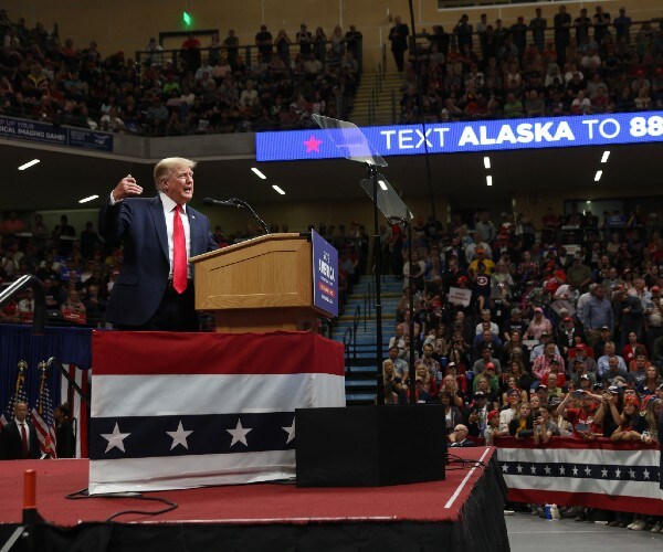 trump on stage with the crowd looking on