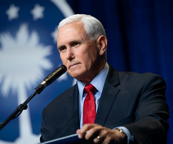 mike pence stands behind podium