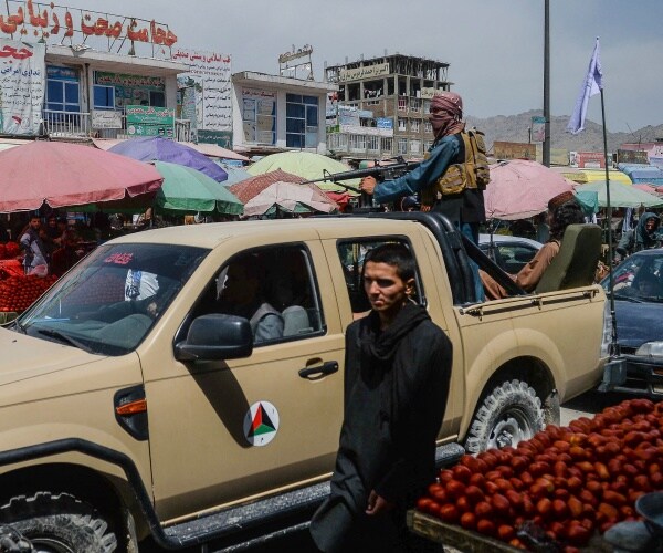 Taliban fighters on a pick-up truck move around a market area.