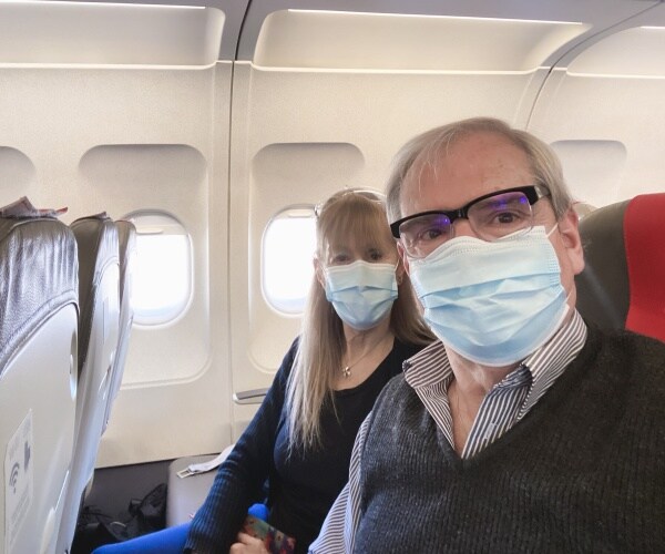 man and woman on plane wearing surgical masks