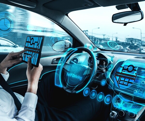 man sits in self driving car holding tablet