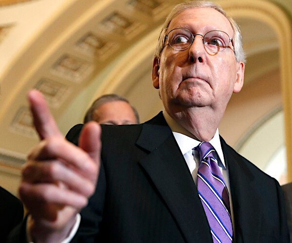 mitch mcconnell points to his right while speaking during a news conference