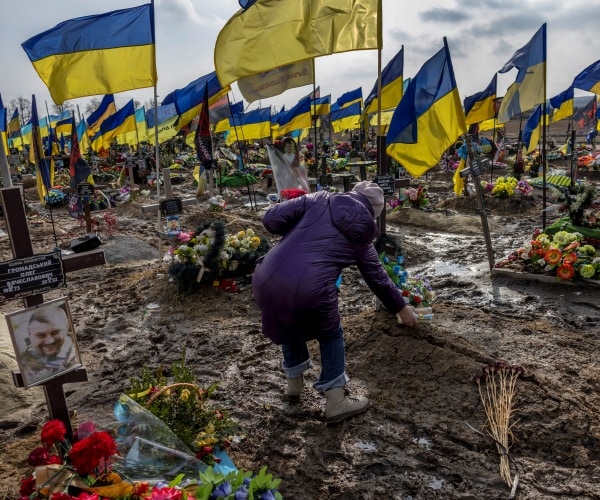 a woman places a container of food atop a grave