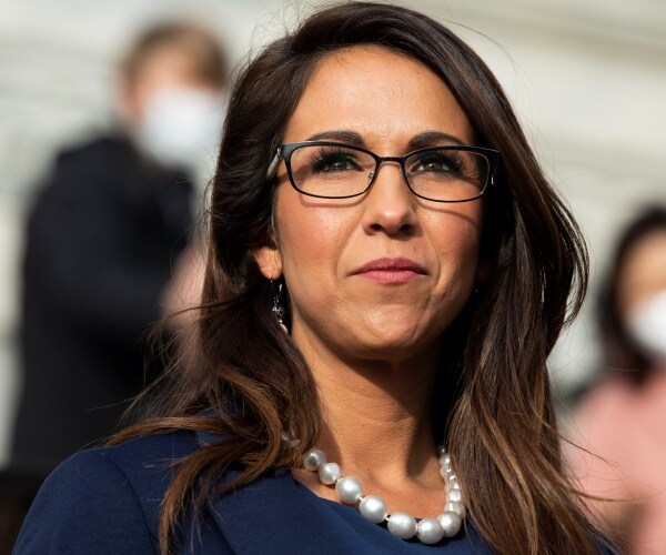 boebert in a navy blue dress and pearl necklace wearing glasses