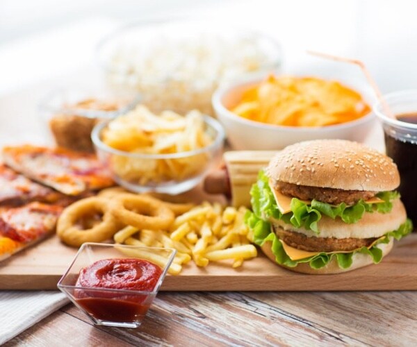 an array of fast foods including hamburger, pizza, fries, soda