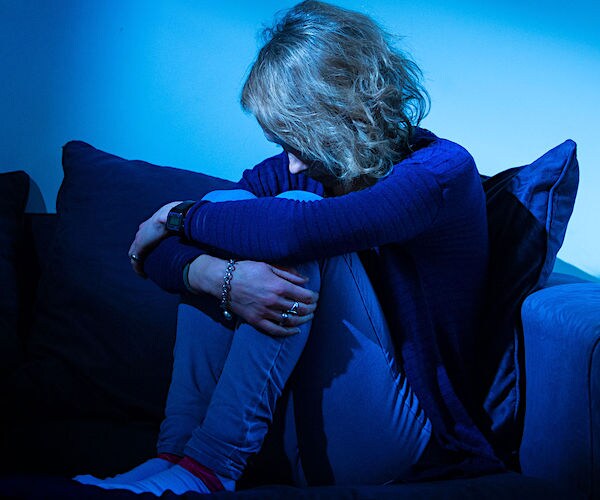 a women buries her head in her knees while seated