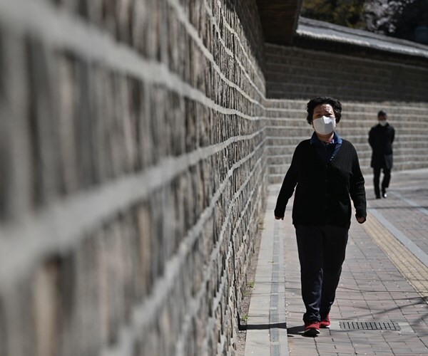 a korean woman wearing a face masks talks a walk