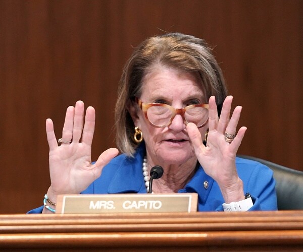 shelley moore capito holds up hands while speaking into mic