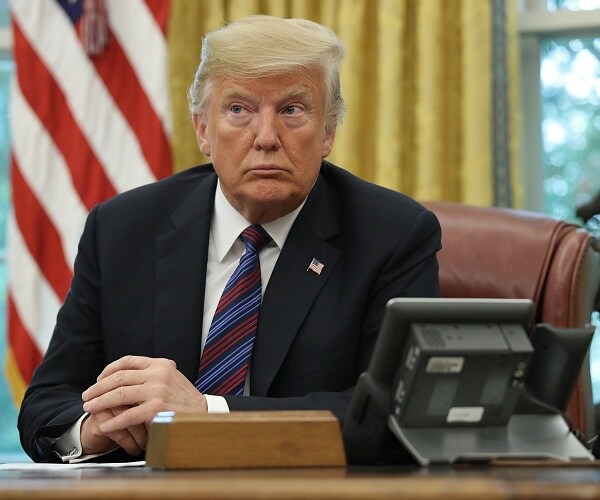 donald trump sits behind desk