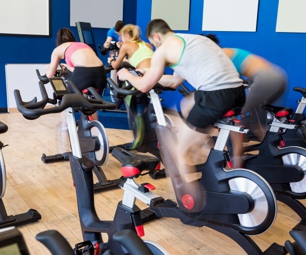 men and women in a gym group cycling class