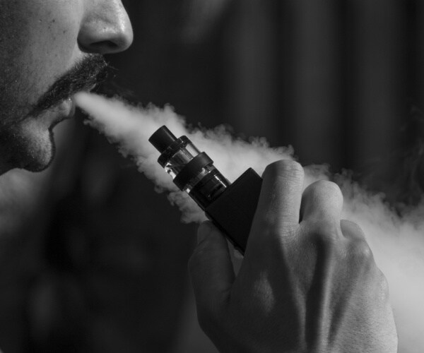 close-up of man blowing out smoke while vaping