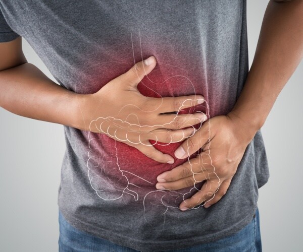 man holds stomach area, outline of colon on image