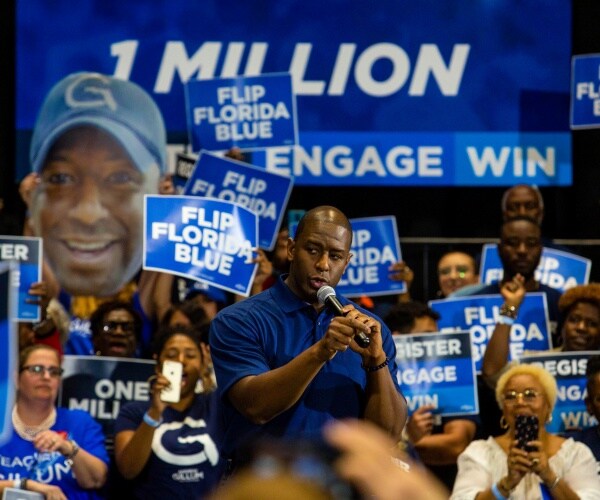 gillum stands in a crowd with posters saying "flip florida blue"