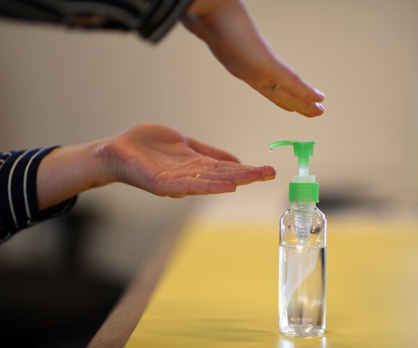 close up of a person's hands pumping hand sanitizer on their hands