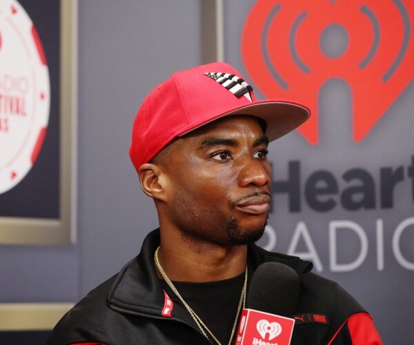 charlamagne the god wearing a red baseball cap and a black shirt with a black and red jacket