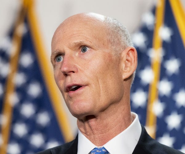 Sen. Rick Scott is shown with the us flag in the background