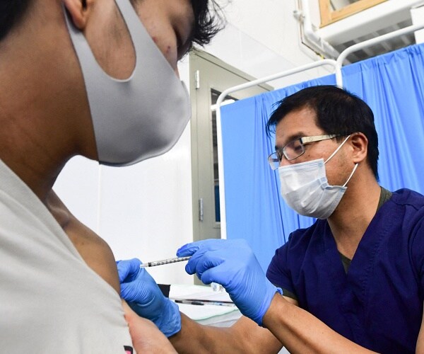 nurse gives young man vaccine shot