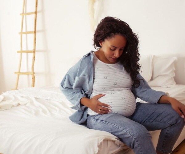 Pregnant woman sitting on bed