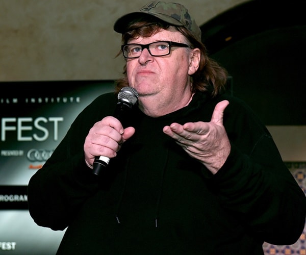 michael moore speaks with a baseball hat on