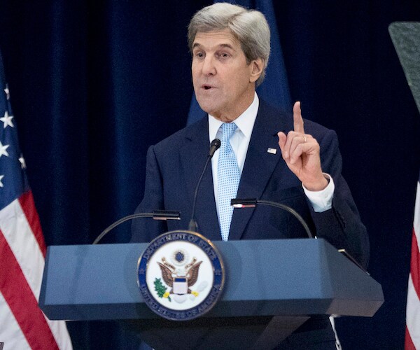 john kerry points up with his left index finger while speaking from a podium