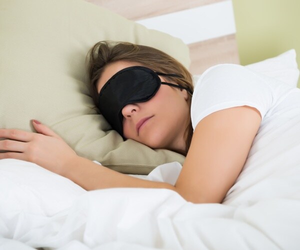 woman wearing dark eye mask in bed