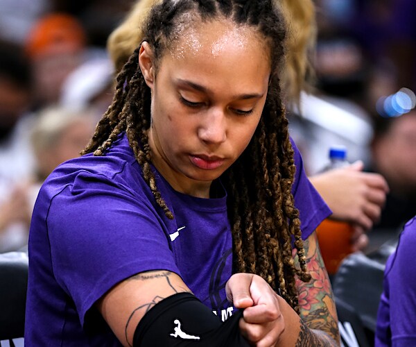 brittney griner adjusts an elbow pad on the bench during a wnba game