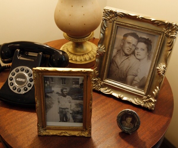 small table with framed pictures of elvis as a teenager and his parents next to a telephone