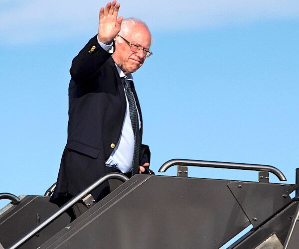 vermont senator bernie sanders waves as he climbs a stairway onto a jet plane