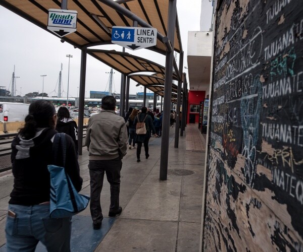 people wearing jackets are seen walking in a train station in a line under the pavilion