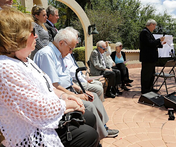 holocaust survivors sit and listen to a speech