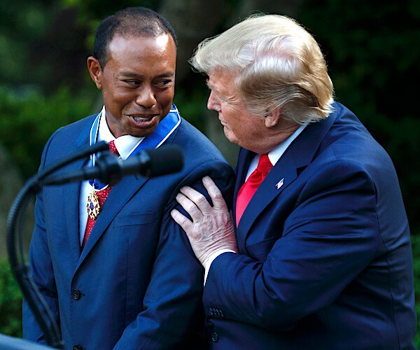 tiger woods looks over as president donald trump embraces him