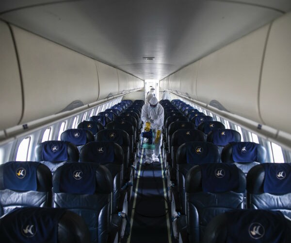 an airline staff member disinfects an empty airplane