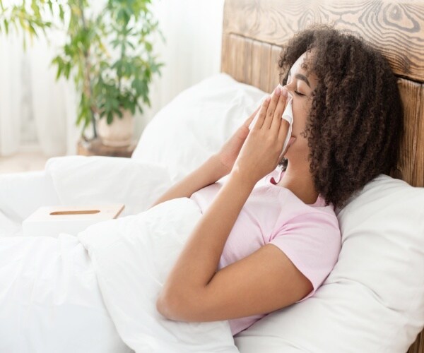 woman in bed blowing her nose