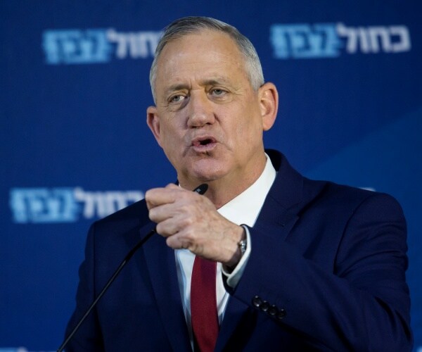 benny gantz speaking wearing a navy blue suit and maroon colored tie with a white shirt