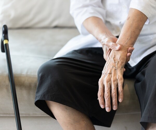 hand with tremor, cane, of woman with Parkinson's