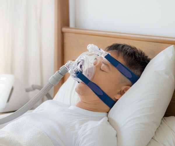 man with cpap therapy mask is shown sleeping in bed